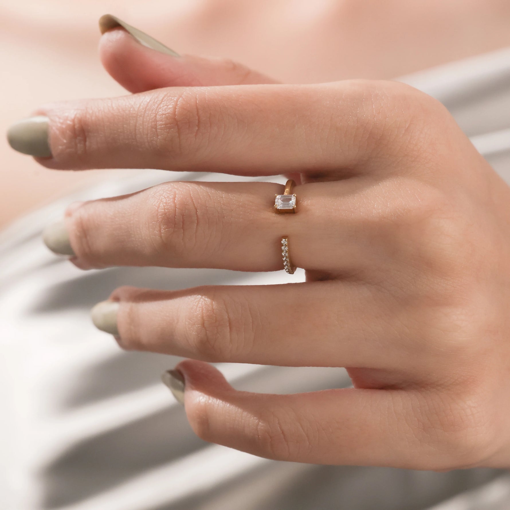 yellow Gold open cuff ring featuring a small emerald cut diamond and round cut pave set band worn on a woman's hand.