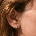 14K Yellow gold emerald, marquise and round diamond stud earring shown worn on ear, held in a delicate prong setting.