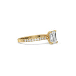 This yellow gold ring displayed in side view is made with a emerald solitaire diamond set in four-prong setting