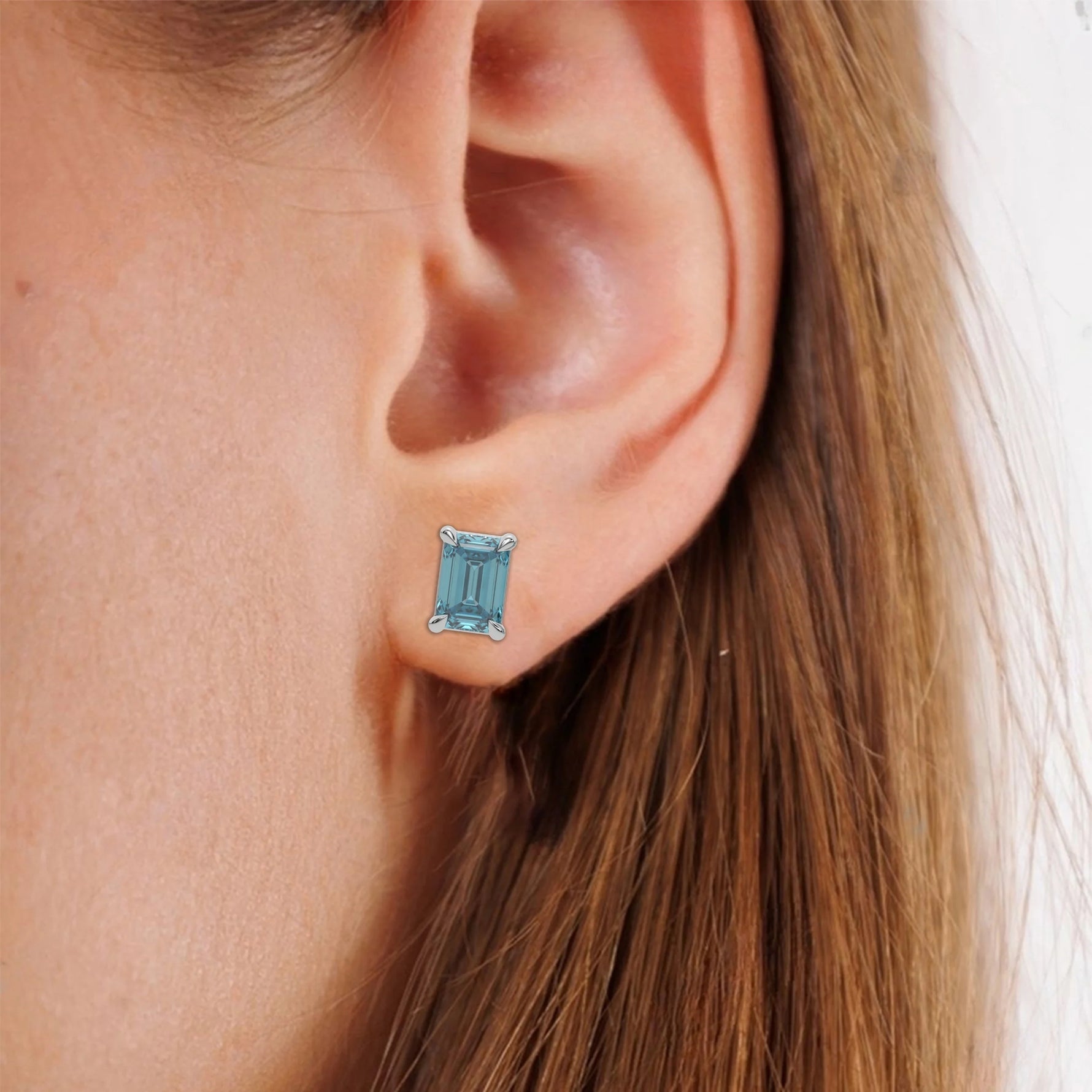 This white gold Classic Emerald Diamond Earrings made with an fancy blue emerald-cut diamonds set in a four prong setting