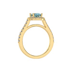 This yellow gold Oval Diamond Halo Engagement Ring is made with a fancy blue oval solitaire diamond set in a four-prong setting, surrounded by a halo of round diamonds all set on a pave band in through finger view