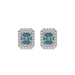 14k white gold Radiant Diamond Halo Earrings made with a fancy blue radiant cut solitaire diamond set in a four prong setting.