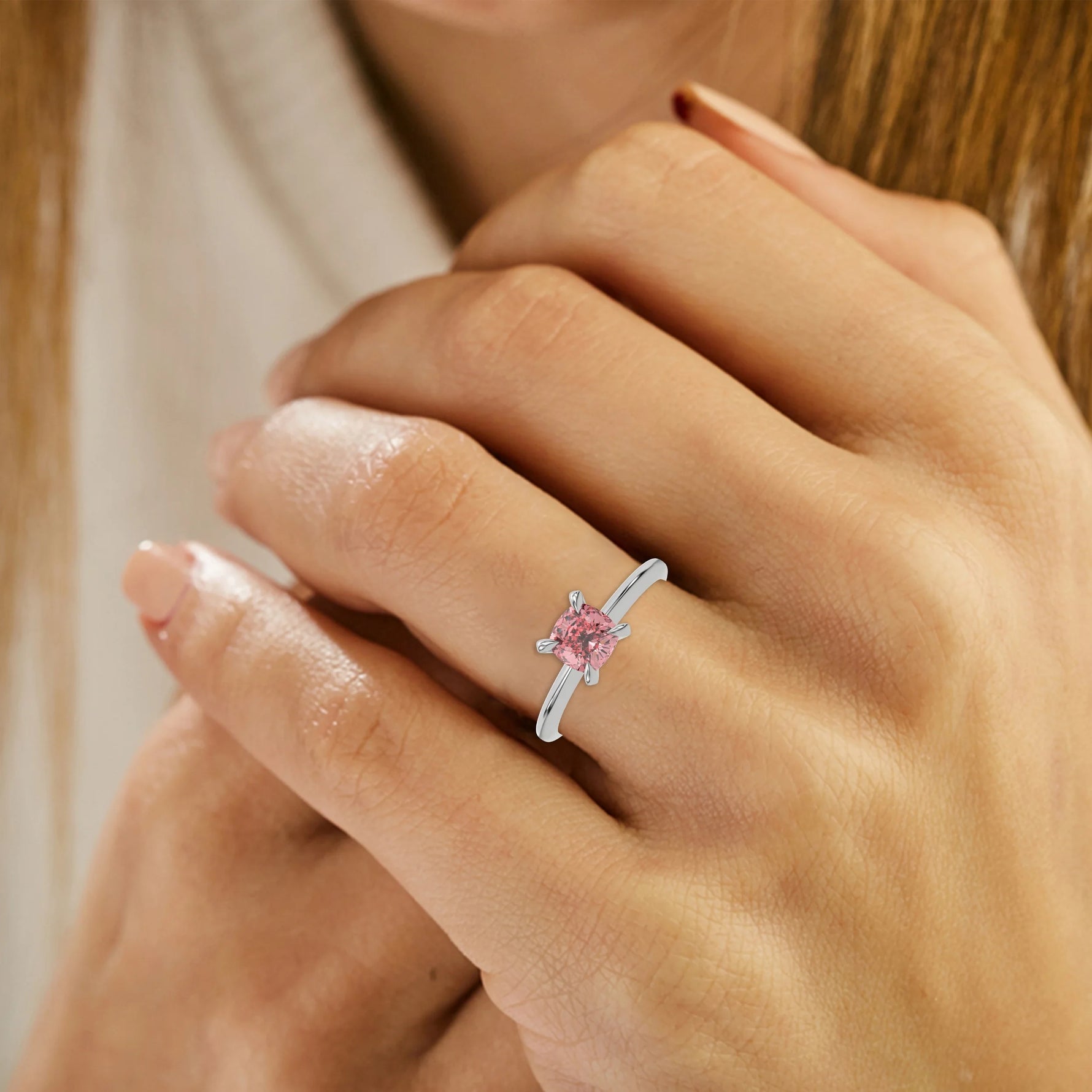 This white gold ring features a fancy Pink cushion solitaire diamond elegantly secured in a four-prong setting on a solid gold band on ring finger