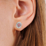 This white gold Classic Oval Diamond Halo Earrings made with an fancy pink oval cut solitaire diamonds set in a four prong setting