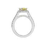 This white gold Oval Diamond Halo Engagement Ring is made with a fancy yellow oval solitaire diamond set in a four-prong setting, surrounded by a halo of round diamonds all set on a pave band in through finger view