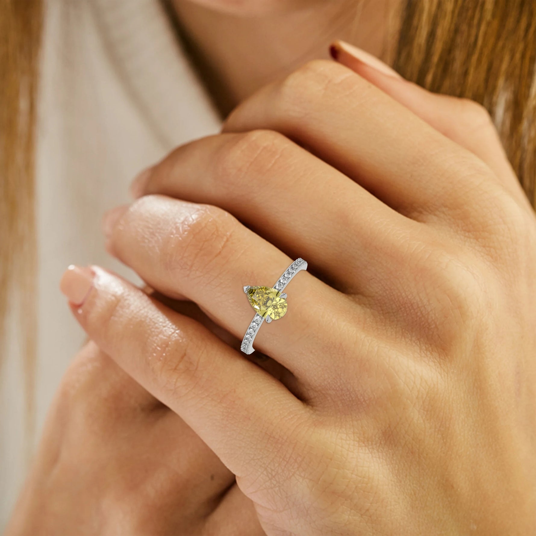 This white gold ring is made with a fancy Yellow pear solitaire diamond set in three-prong setting, and is complemented by a round pave diamonds band on ring finger