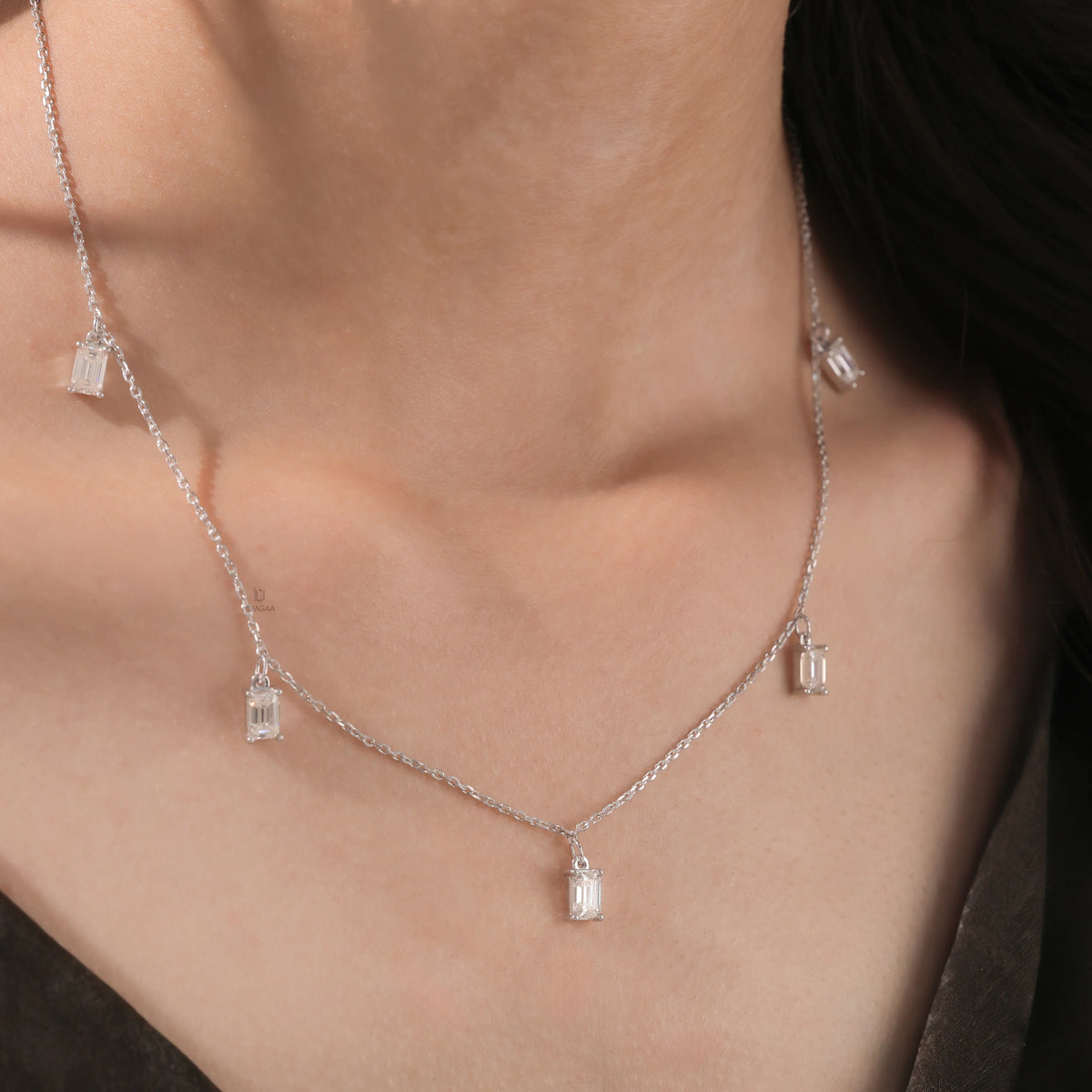 Model wearing a yellow gold Emerald diamond Dangling necklace featuring prong-set emerald-cut diamond charms along a fine chain.