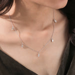 Model wearing a yellow gold Emerald diamond Dangling necklace featuring prong-set emerald-cut diamond charms along a fine chain.