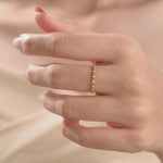 Close-up of a woman's hand wearing a textured yellow gold stackable ring with spaced round diamonds band.