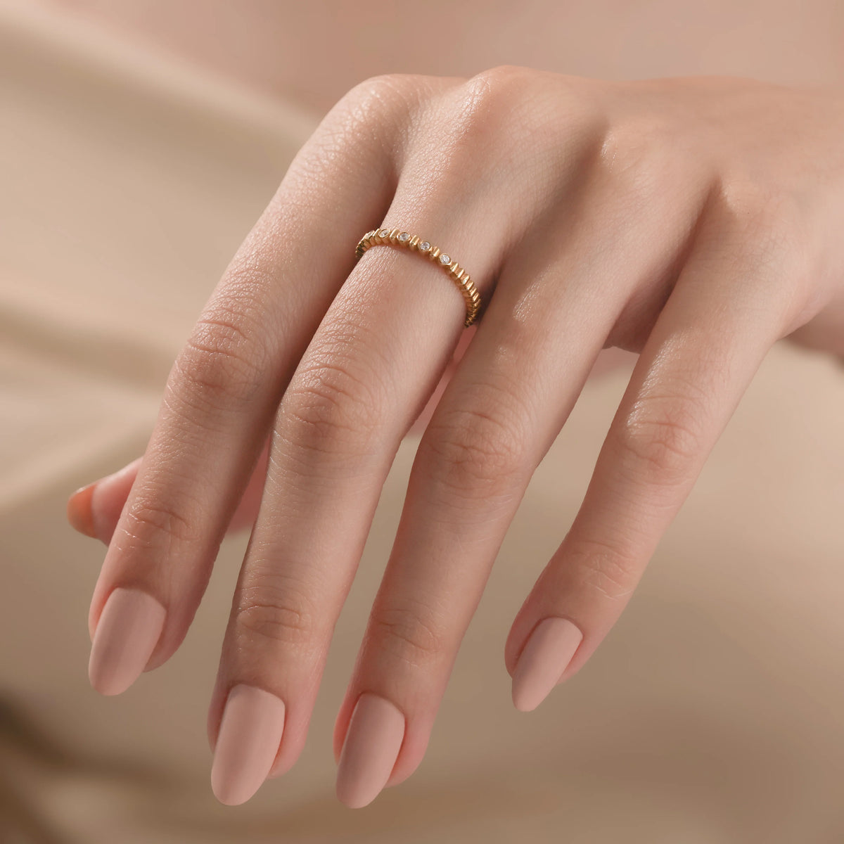 Modern yellow gold bubble style band with bezel set diamond accents, shown close-up on a model's hand to showcase real-life fit.