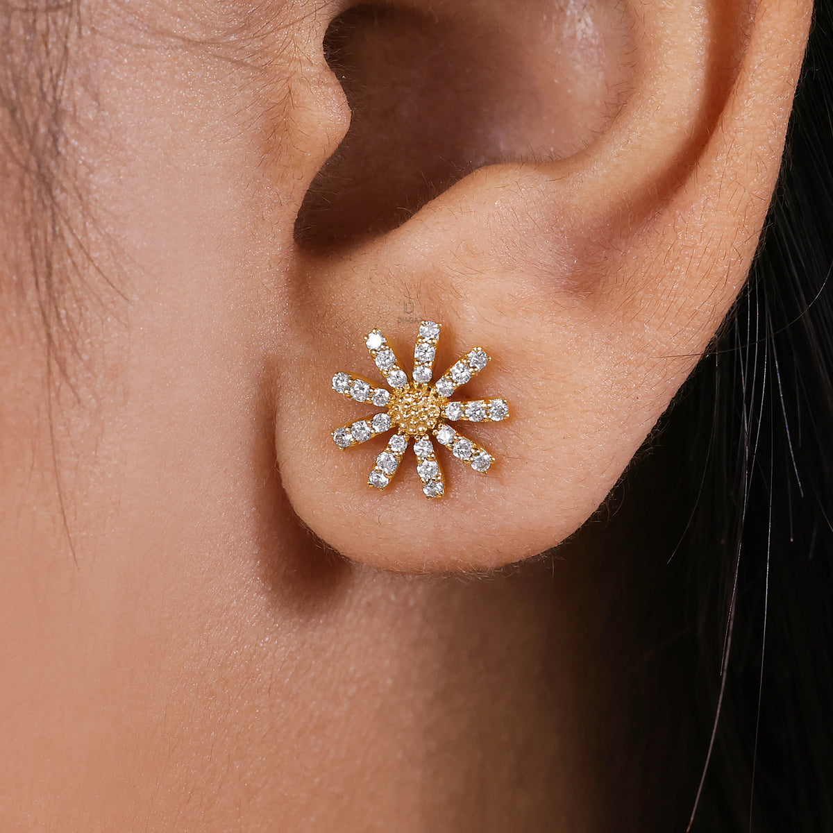 Model wearing a yellow gold daisy earring showing the relative size and sparkle of the pavé crystal petals against the earlobe.