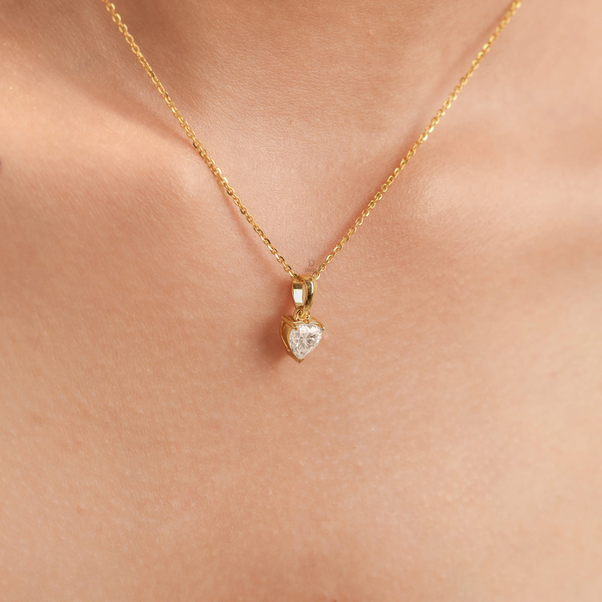 Woman wearing a delicate 18K yellow gold heart diamond necklace featuring a prong-set heart solitaire pendant.