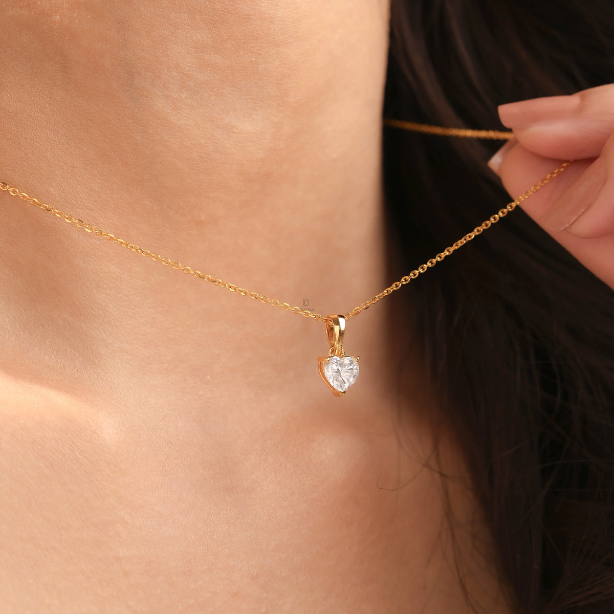 Woman wearing a delicate yellow gold heart diamond necklace featuring a prong-set heart solitaire pendant.