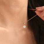 Woman wearing a delicate yellow gold heart diamond necklace featuring a prong-set heart solitaire pendant.