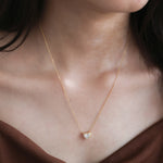 Model wearing a delicate bezel-set heart diamond necklace in yellow gold, featuring a brilliant heart-cut stone on a fine gold chain.