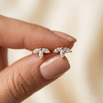 Elegant cluster marquise diamond stud earring, prong-set in yellow gold, held between fingers with a subtle half flower design.