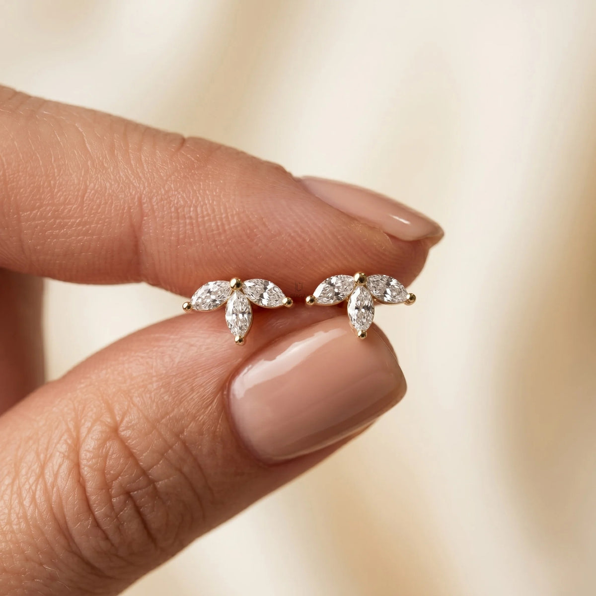 Elegant cluster marquise diamond stud earring, prong-set in yellow gold, held between fingers with a subtle half flower design.