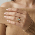 Yellow gold east-west marquise diamond ring with a pavé set, worn on a hand against a brown sweater.