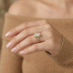 Marquise cut diamond engagement ring with a yellow gold bezel setting worn on a woman's hand.
