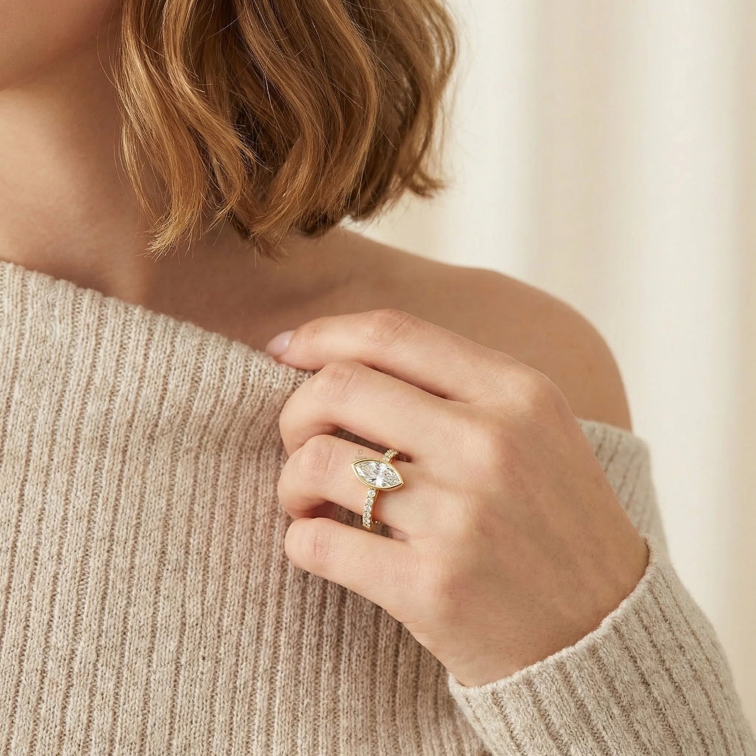 Modern yellow gold bezel solitaire ring with an east-west marquise diamond and a sparkling diamond accented band, displayed gracefully on a hand for an elegant bridal look.