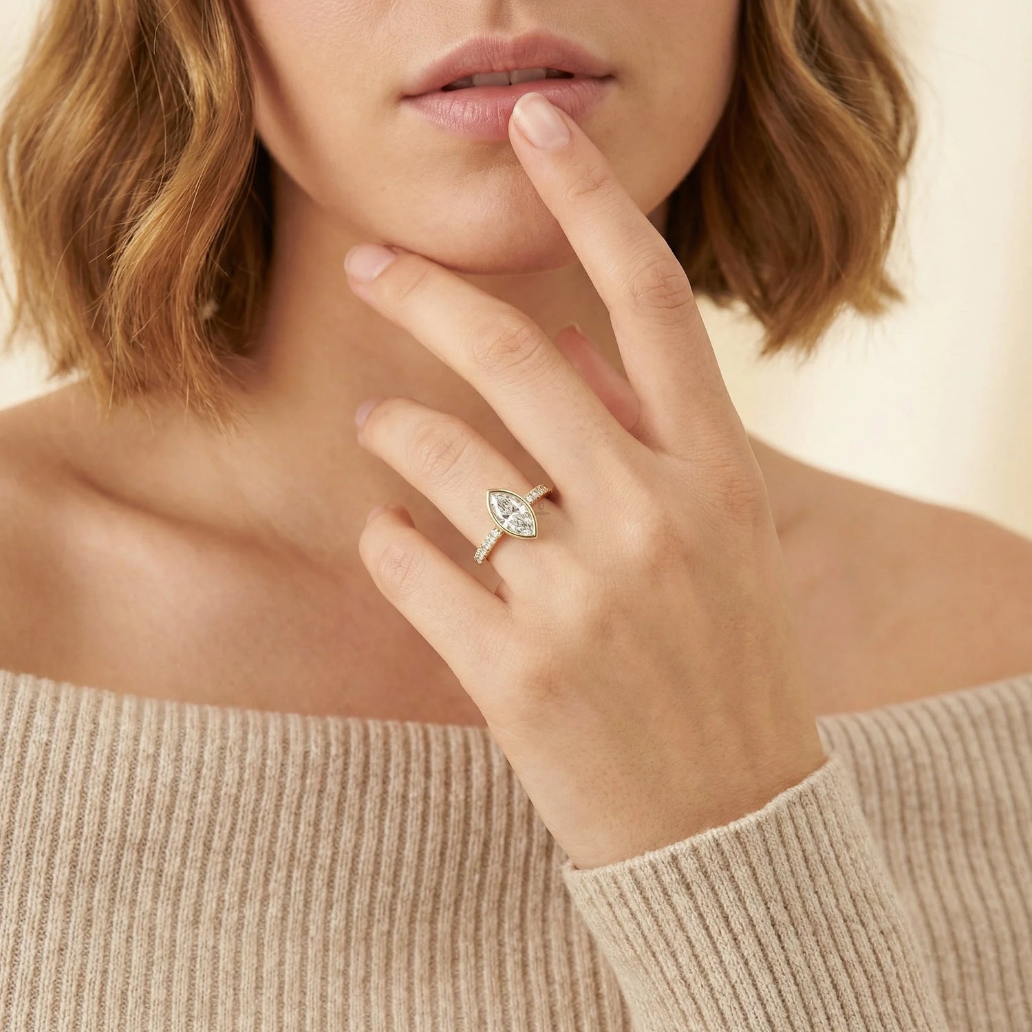 Model lifestyle photo of a 18k gold marquise diamond ring featuring a secure low-profile bezel setting and micro-pavé band, showcasing luxury jewelry on a hand.