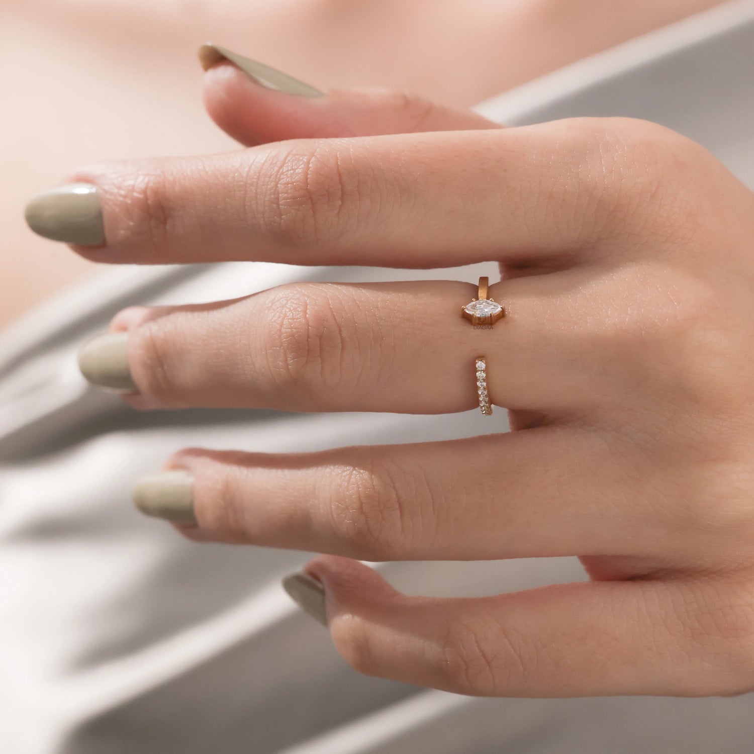 Yellow gold open cuff ring with a marquise cut diamond and small round diamond pave set band worn on a woman's index finger.