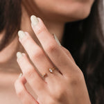 Close-up of a woman's hand wearing a minimalist gold open ring featuring a marquise-cut diamond and pave accents.