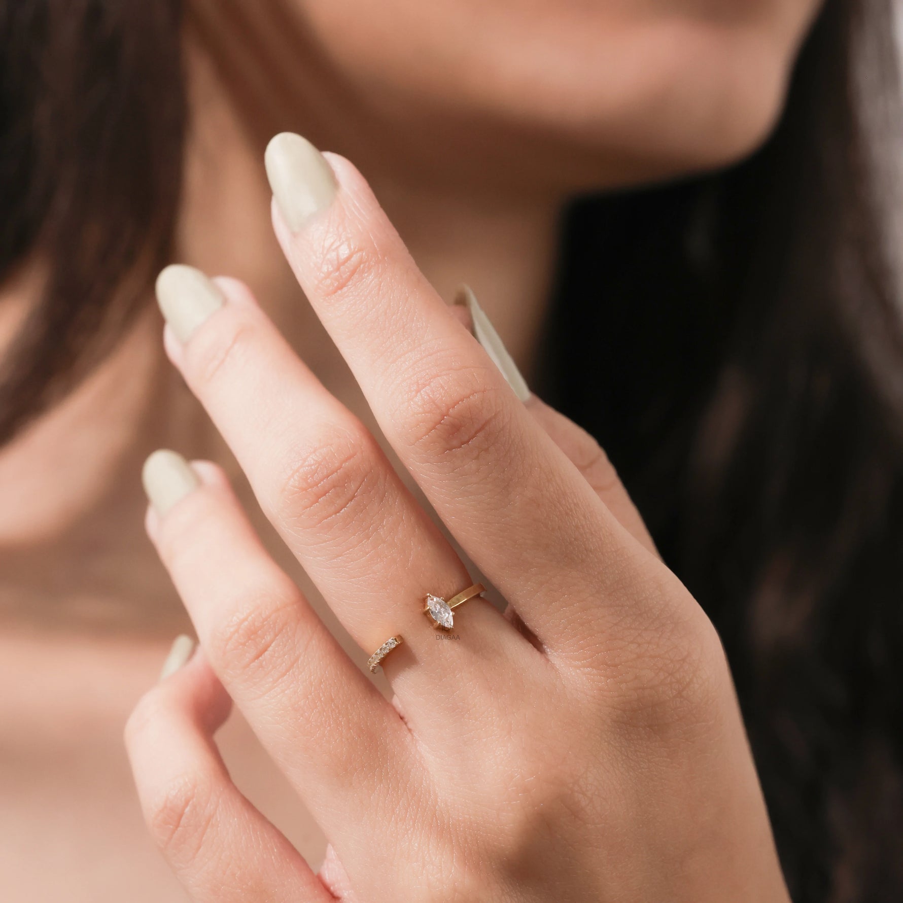 Close-up of a woman's hand wearing a minimalist gold open ring featuring a marquise-cut diamond and pave accents.