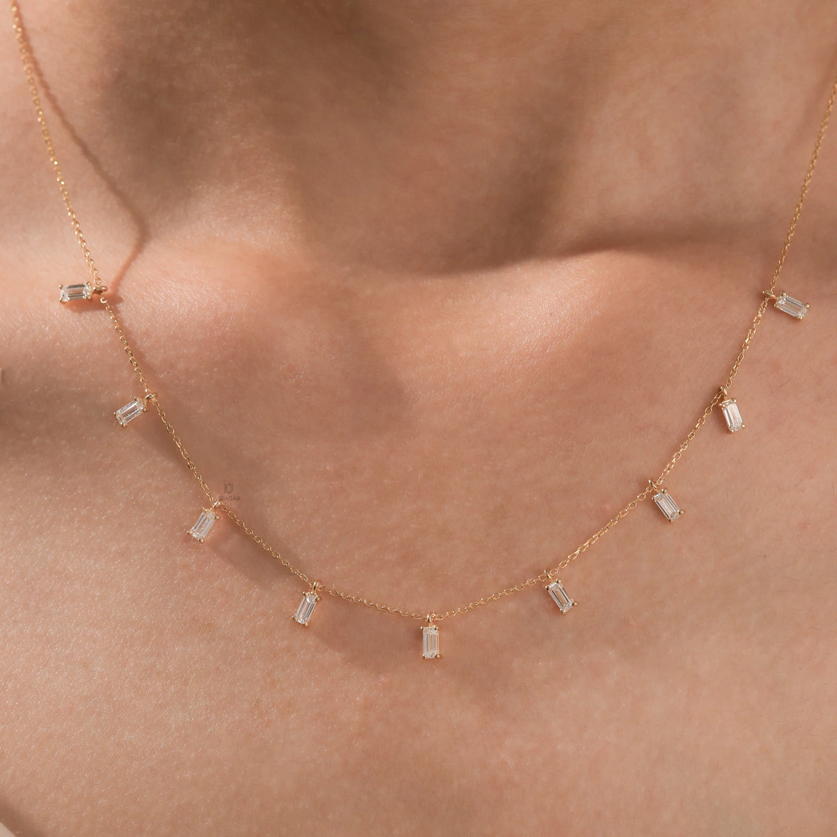 Model wearing a yellow gold Emerald diamond Dangling necklace featuring nine prong-set emerald-cut diamond charms along a fine chain.