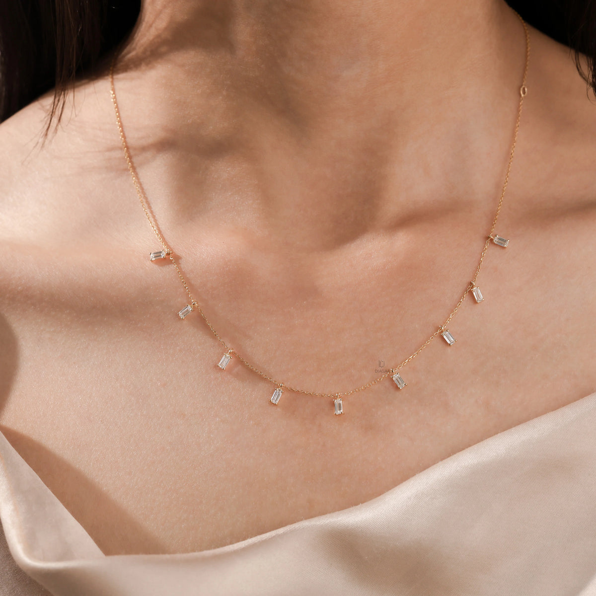 Model wearing a yellow gold Emerald diamond Dangling necklace featuring nine prong-set emerald-cut diamond charms along a fine chain.