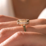 Close-up side profile of a yellow gold engagement ring featuring a bezel-set center stone and a sparkling hidden halo round diamond on a finger.