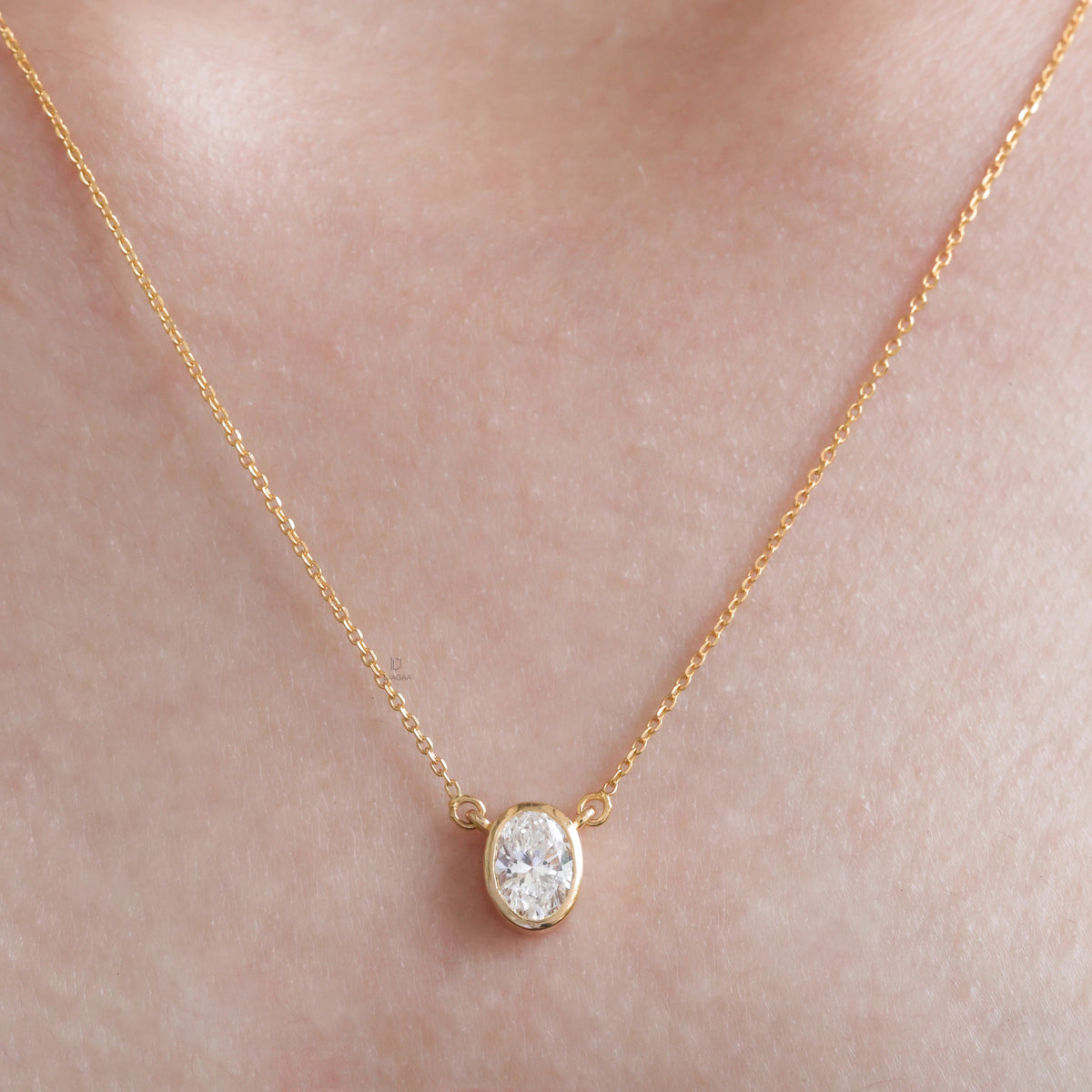 Model wearing a classic yellow gold Oval Diamond necklace featuring a bezel-set solitaire pendant.