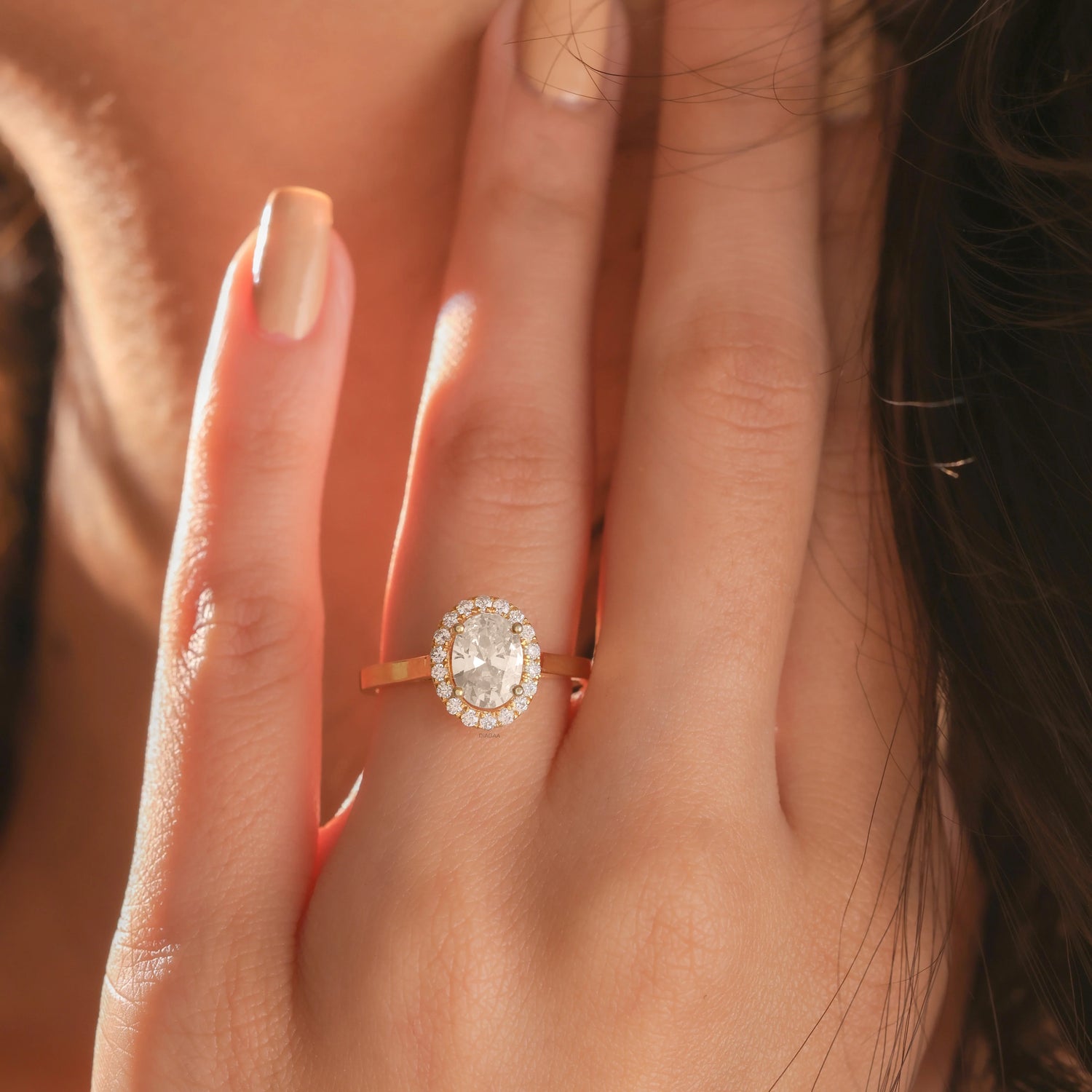 Hand modeled view of a yellow gold ring showcasing a Solitaire oval diamond ring. An elegant oval diamond ring crafted as a round diamond halo set ring gold ring style.