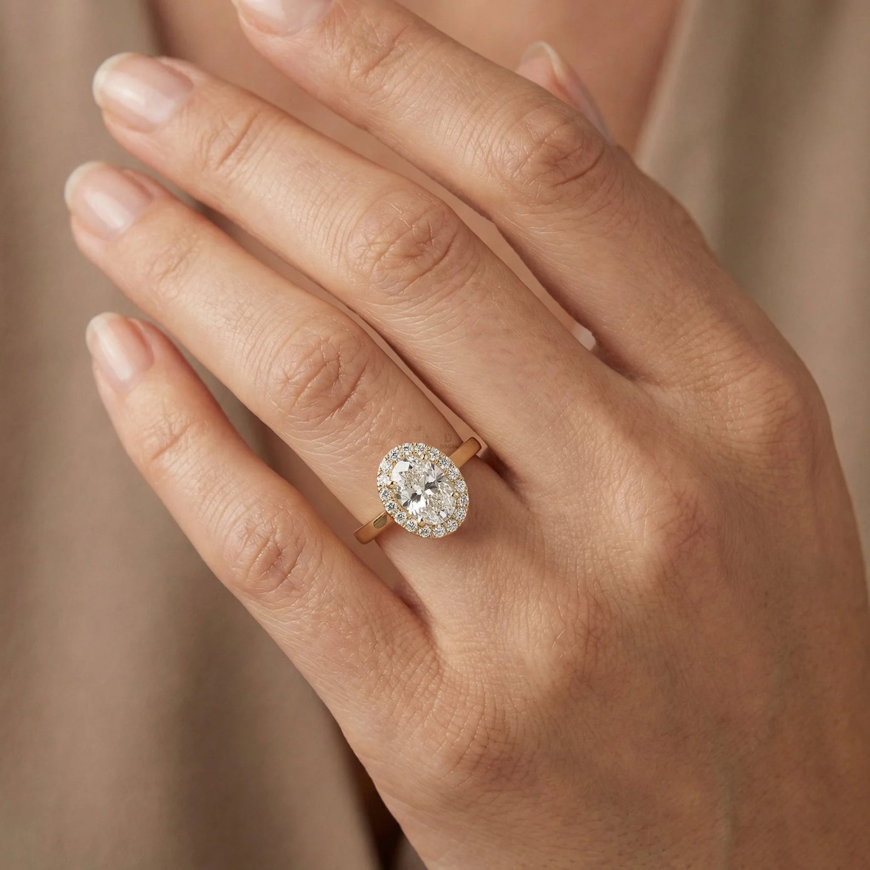 hand wearing a this elegant yellow gold ring unique oval center stone ring,designed as a round diamond halo set solitaire oval diamond engagement ring 