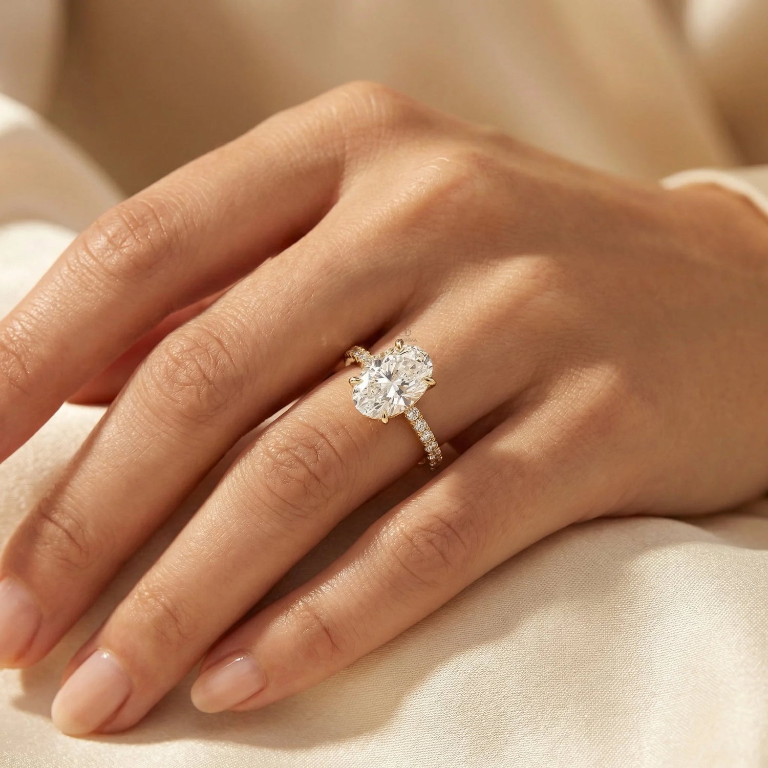 Oval cut diamond engagement ring featuring a large brilliant center stone and a yellow gold round cut siad stone pavé diamond band on a finger.