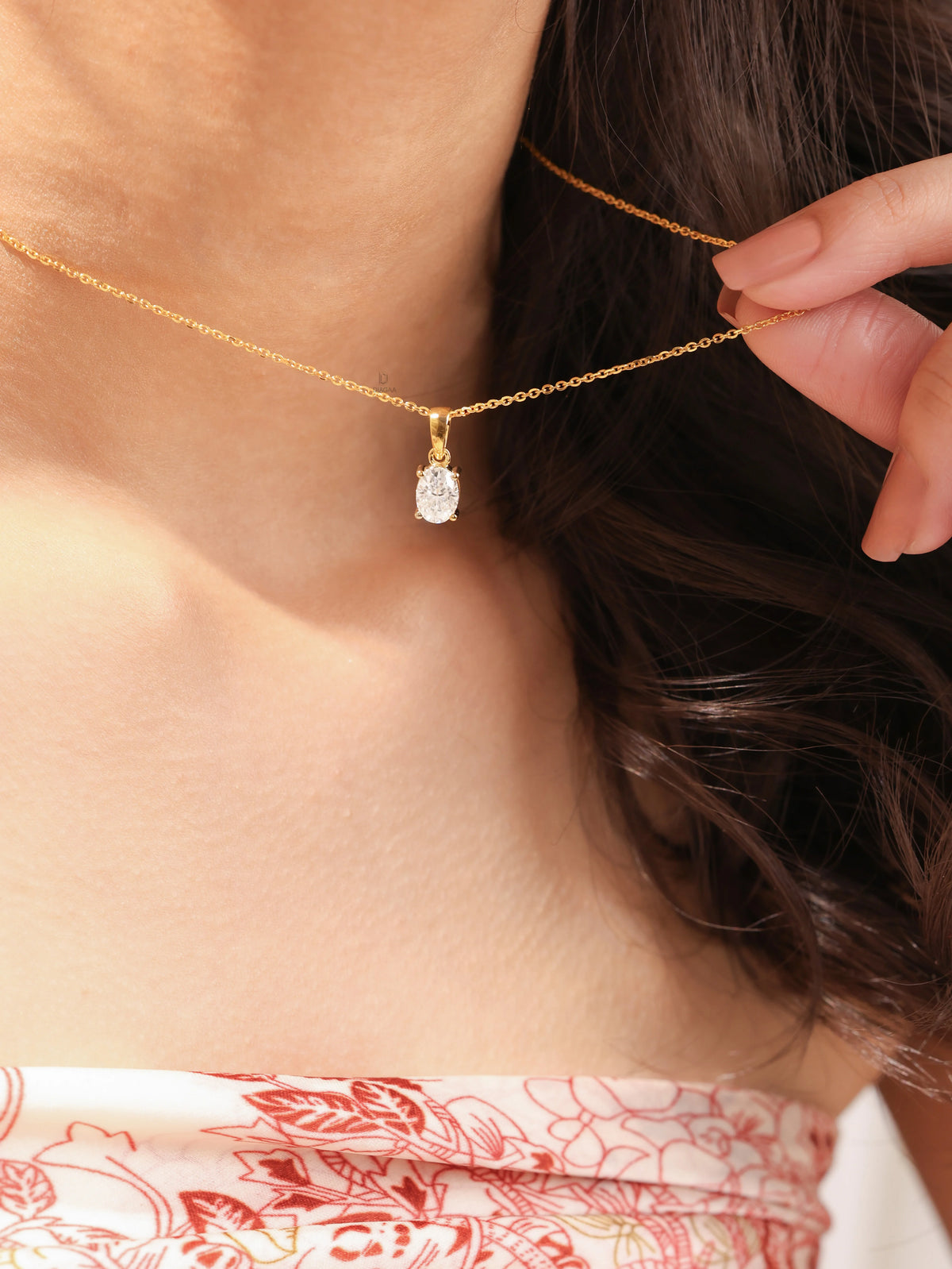Woman wearing a delicate yellow gold oval diamond necklace featuring a prong-set solitaire pendant.