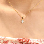 Woman wearing a delicate yellow gold oval diamond necklace featuring a prong-set solitaire pendant.