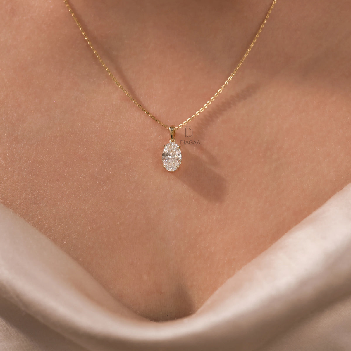 Woman wearing a delicate 14K yellow gold oval diamond necklace featuring a sparkling prong-set solitaire pendant.