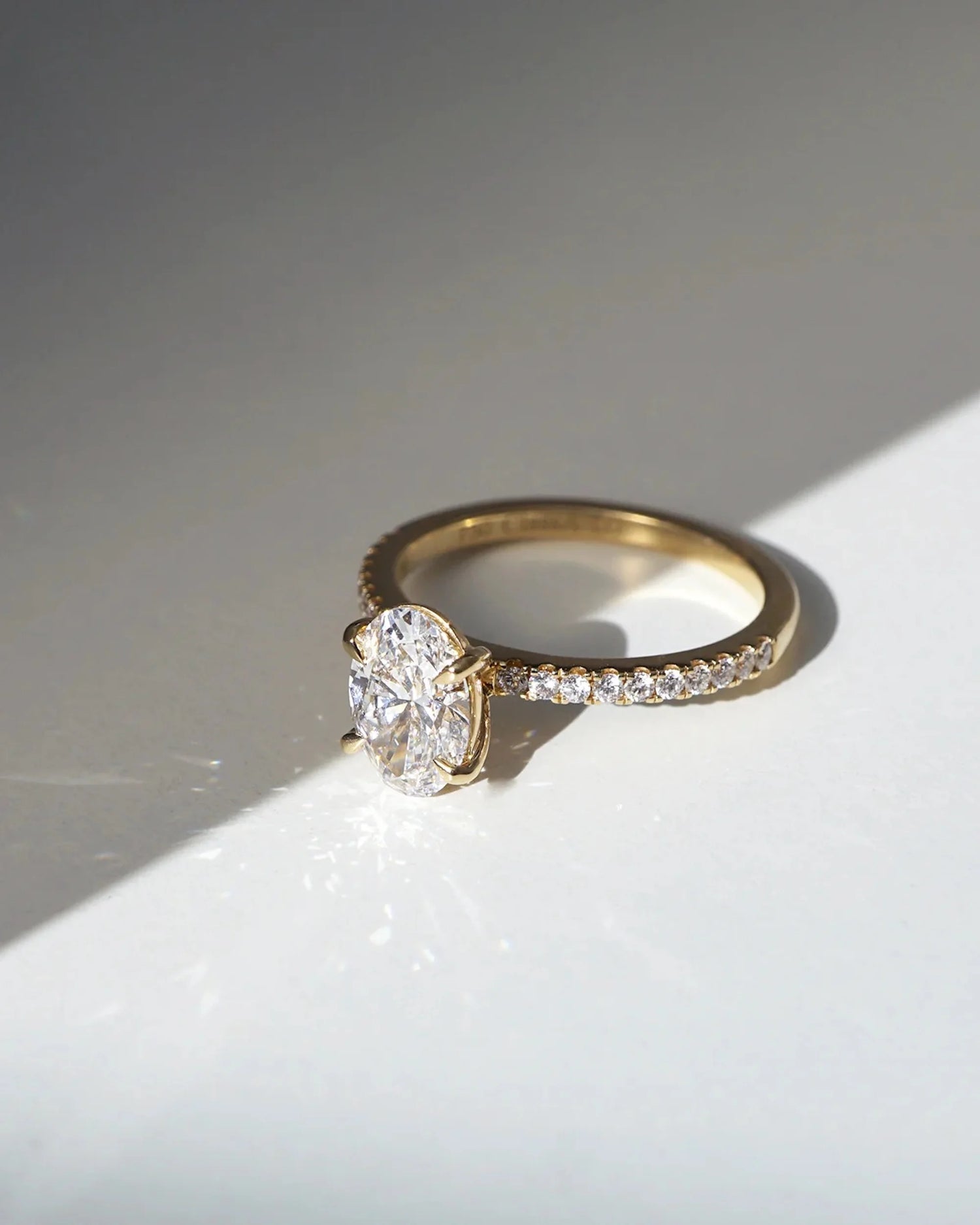 This yellow gold ring displayed in front view is made with a oval solitaire diamond set in four-prong setting