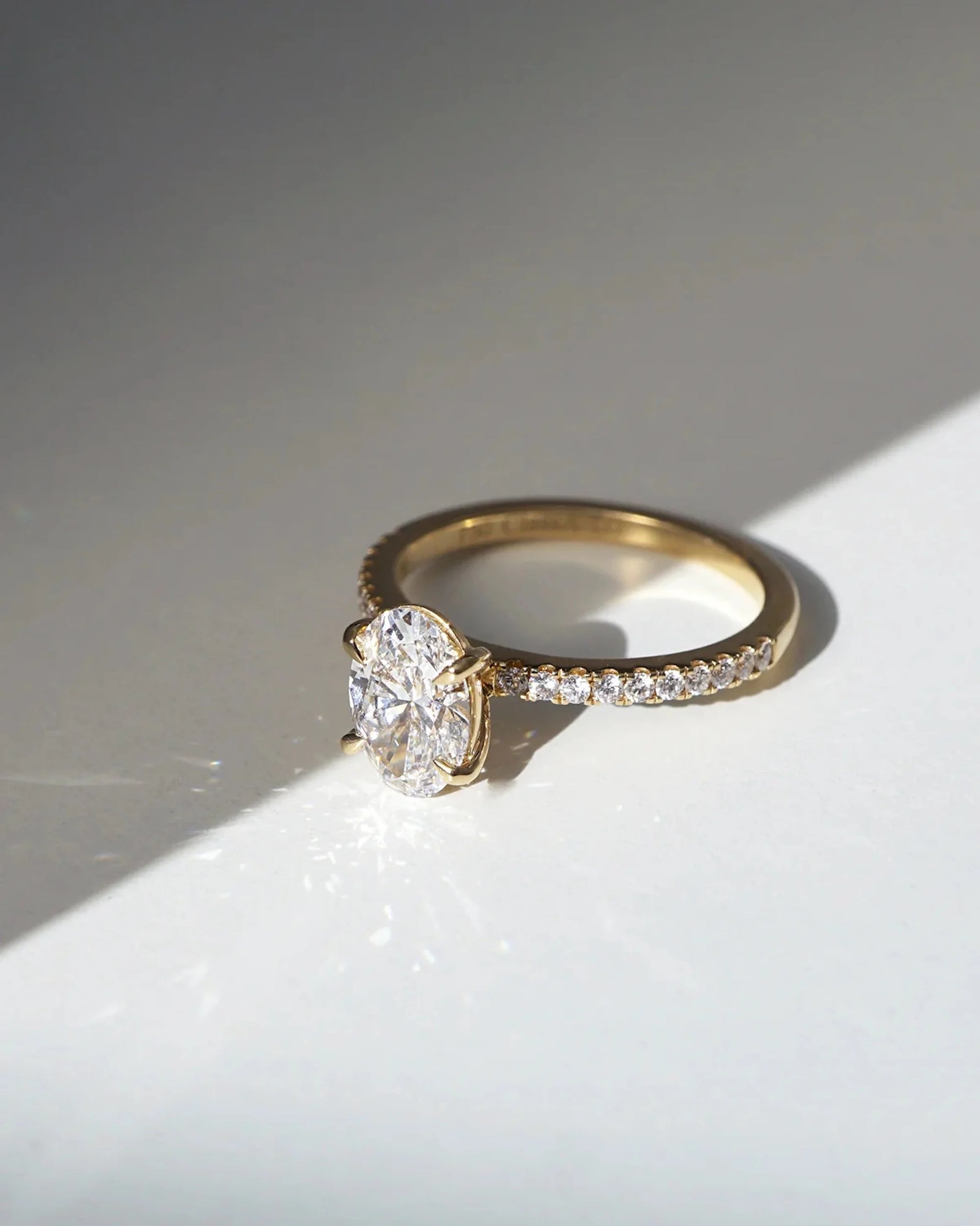 This yellow gold ring displayed in front view is made with a oval solitaire diamond set in four-prong setting