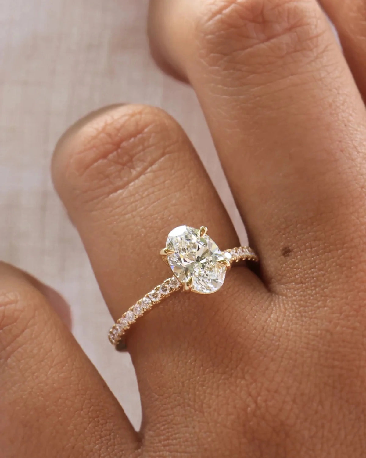 This yellow gold ring displayed in front view is made with a oval solitaire diamond set in four-prong setting