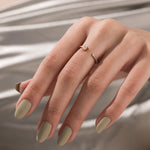 Yellow gold open cuff ring with an oval cut diamond and small pave band worn on a woman's middle finger.