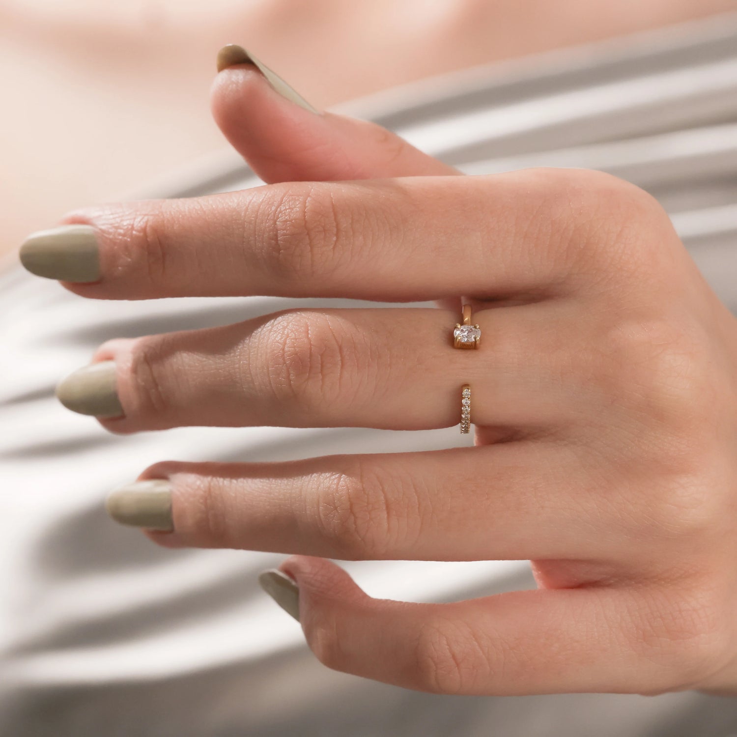 Yellow gold open cuff ring with a small oval cut diamond and pave diamond band worn on a woman's hand.