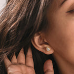 Side profile portrait of a woman showcasing a yellow gold pear cut diamond stud earring set in a smooth bezel frame. Modern daily jewelry.