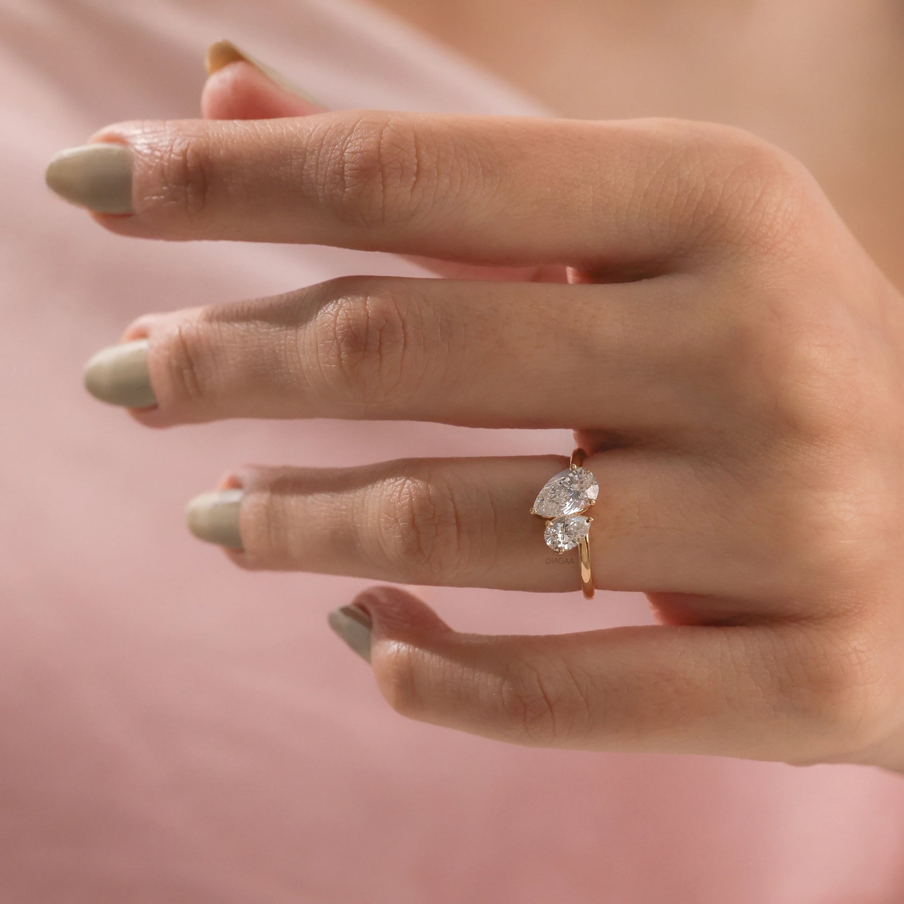 Stunning Toi et Moi engagement ring in 10K yellow gold featuring a pear cut ring design with two sparkling diamonds on a hand.
