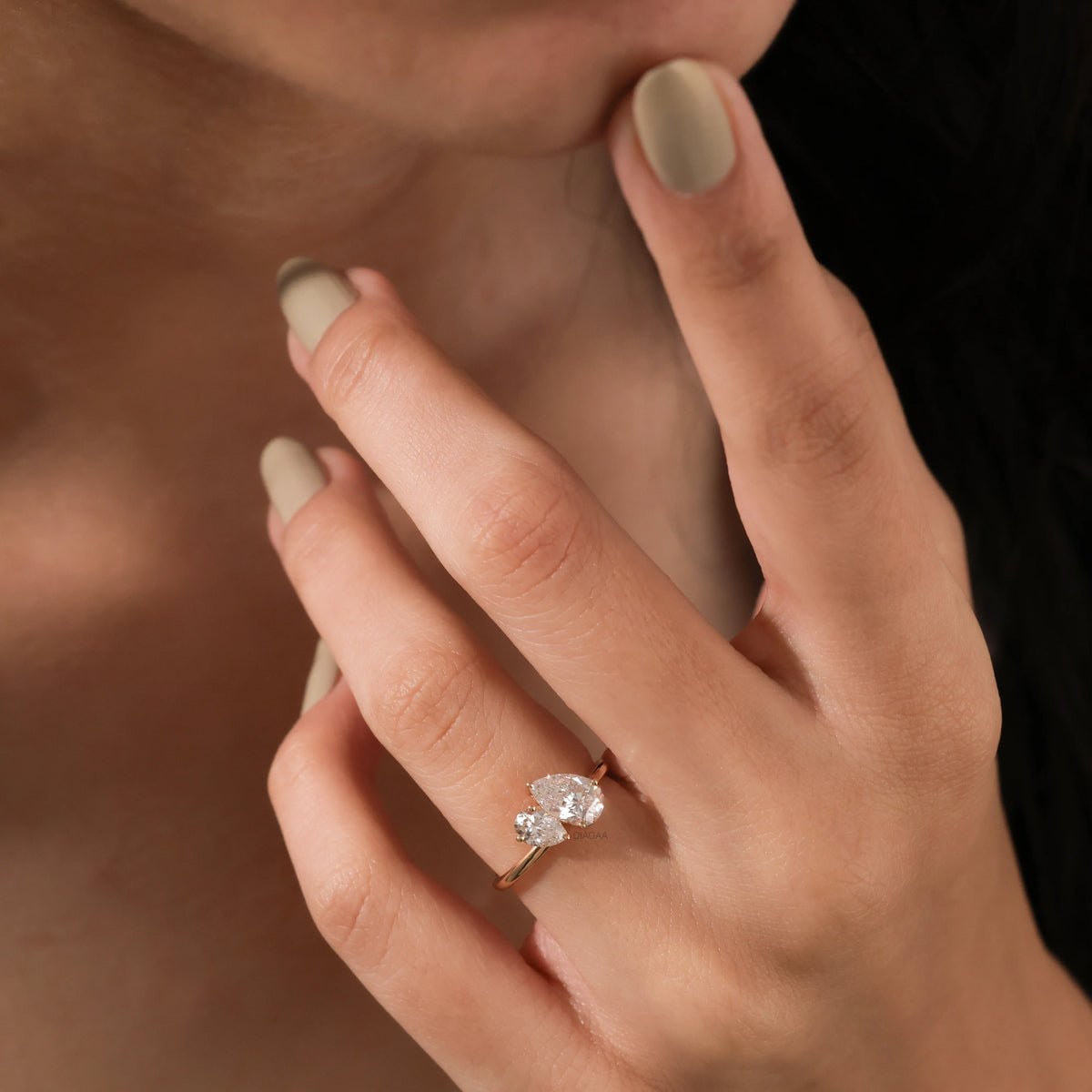 Stunning Toi et Moi engagement ring in yellow gold featuring a pear cut ring design with two sparkling diamonds on a hand.