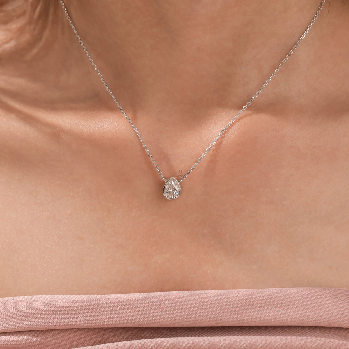 Model wearing a classic 18K white gold Pear Diamond necklace featuring a teardrop bezel-set solitaire pendant.