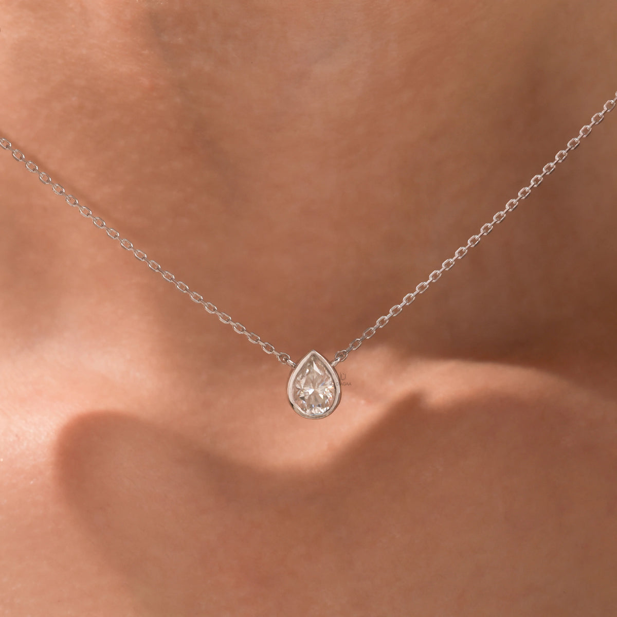 Model wearing a classic white gold Pear Diamond necklace featuring a teardrop bezel-set solitaire pendant.