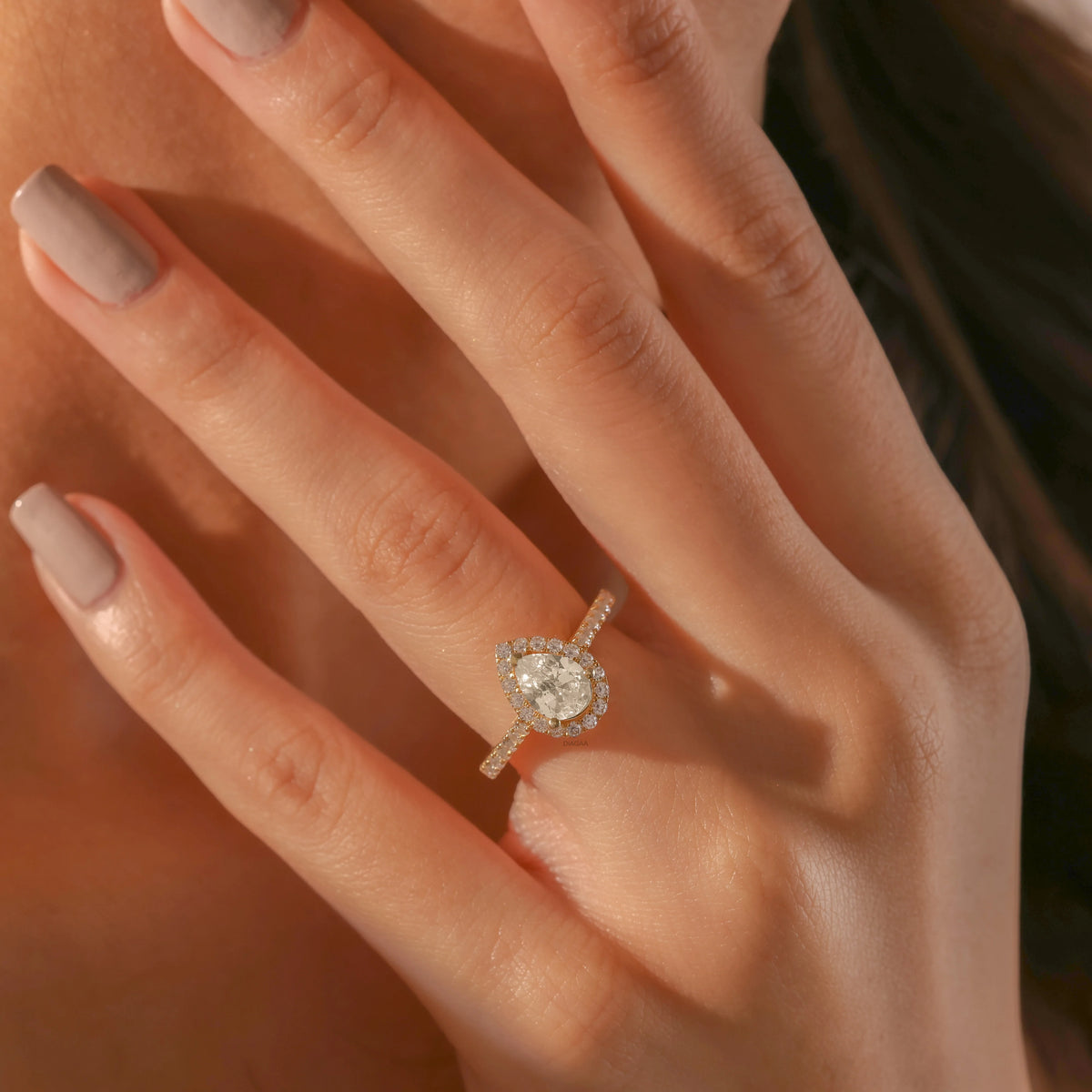 Yellow gold engagement ring with a large pear-shaped diamond and a sparkling diamond halo and pave band.