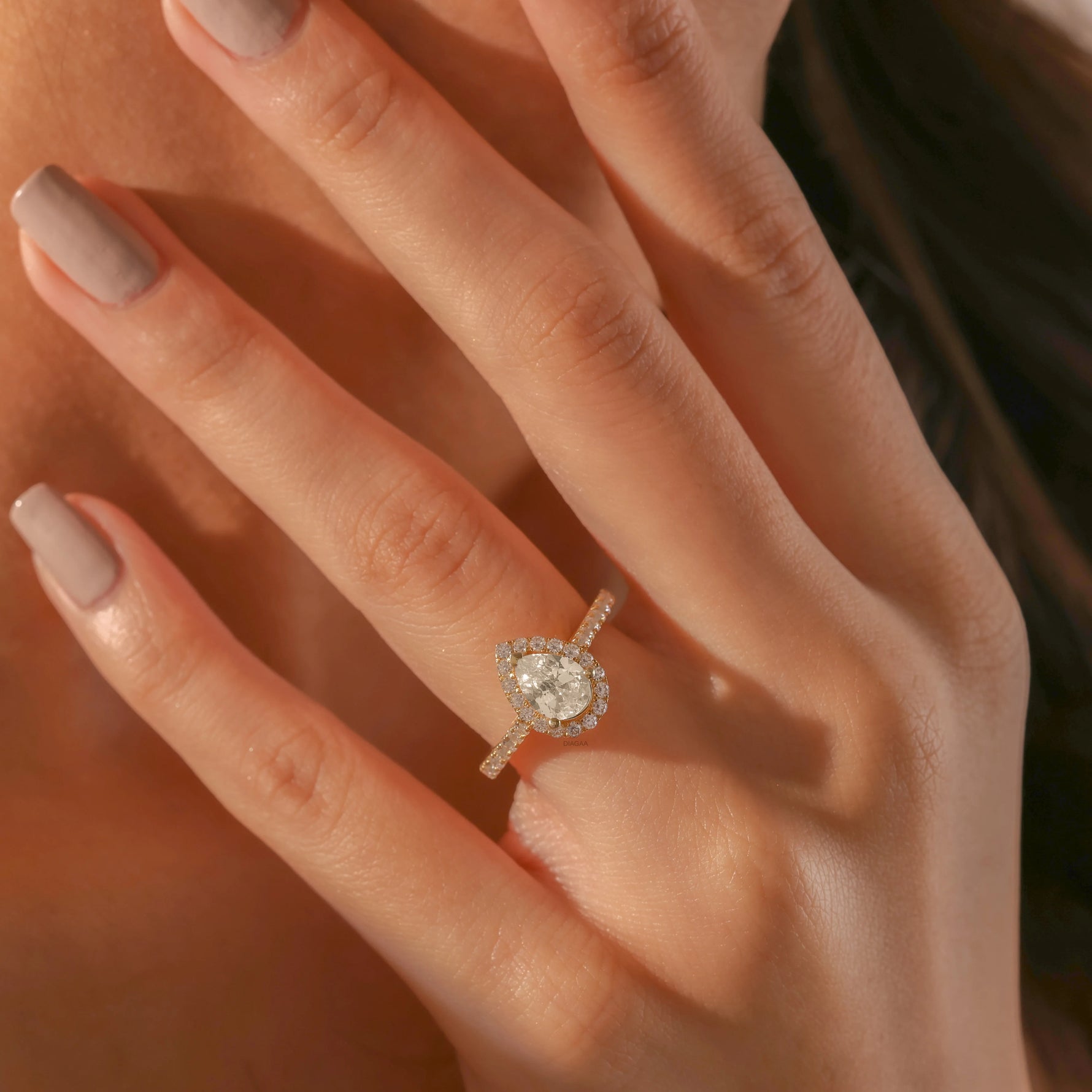 Yellow gold engagement ring with a large pear-shaped diamond and a sparkling diamond halo and pave band.